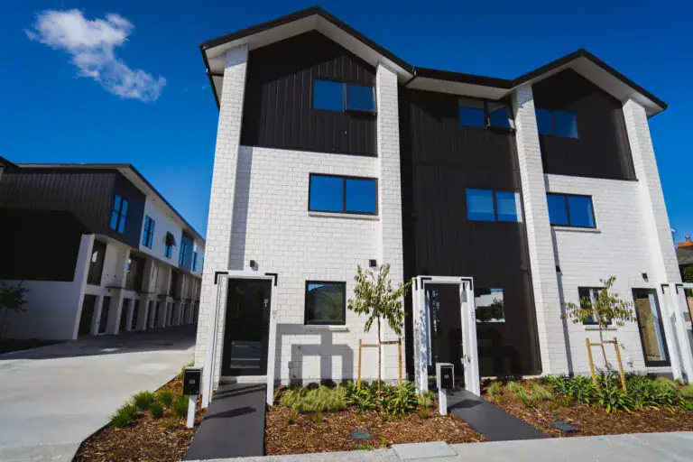 Completed homes with white brick, dark cladding and landscaped paths at 200 Carrington Road, Auckland